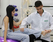 Aluno da Faculdade de Terapia Ocupacional em Jaú realizando atendimento e exame em paciente na clínica, focando em reabilitação física.