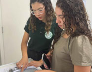 Alunas da Faculdade de Terapia Ocupacional em Jaú em aula prática, utilizando equipamentos e discutindo procedimentos em ambiente de laboratório.
