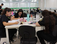 Alunas da Faculdade de Estética e Cosmética em Jaú estudando em sala de aula, concentradas em seus materiais e notebooks.