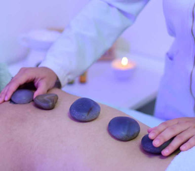Aluna da Faculdade de Estética e Cosmética em Jaú realizando massagem com pedras quentes, ilustrando as habilidades terapêuticas e o perfil profissional do curso.