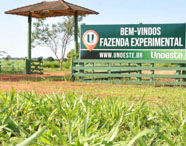 Placa de boas-vindas à Fazenda Experimental da Faculdade de Biotecnologia em Presidente Prudente, com área verde e estrutura de madeira.