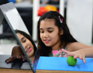 Terapeuta ocupacional ou aluna realizando atendimento infantil, com criança brincando com bola e espelho, focando em desenvolvimento e reabilitação.