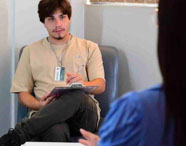 Aluno da Faculdade de Terapia Ocupacional e paciente em sessão de reabilitação com jogo de argolas na clínica-escola, promovendo coordenação e destreza.