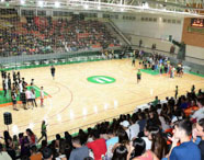 Ginásio de esportes da Faculdade de Terapia Ocupacional lotado durante gincana de calouros, com estudantes na quadra e arquibancadas, promovendo integração.