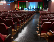 Interior do Teatro César Cava, palco de eventos acadêmicos da Faculdade de Terapia Ocupacional, com poltronas vazias e palco iluminado.