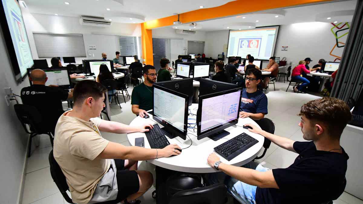 Alunos de Sistemas de Informação em aula prática no laboratório de criação, trabalhando colaborativamente em computadores para desenvolvimento de software e projetos de tecnologia.