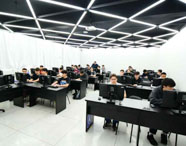 Vista ampla do laboratório de informática da Faculdade de Sistemas de Informação, com teto geométrico e alunos concentrados em seus computadores.