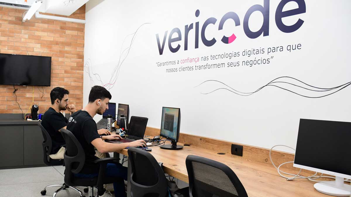 Desenvolvedores de software trabalhando em um ambiente de startup ou sala de talentos, focados em programação e projetos de tecnologia para "Vericode", destacando inovação e TI.