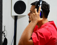 Estudante da Unoeste realizando exame de audiometria com fones de ouvido em cabine preparada. 