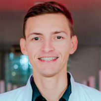 Matheus, aluno do curso de odontologia, trajando jaleco branco sobre uma camisa preta. Ele está em um ambiente interno com iluminação colorida ao fundo, criando um cenário moderno.