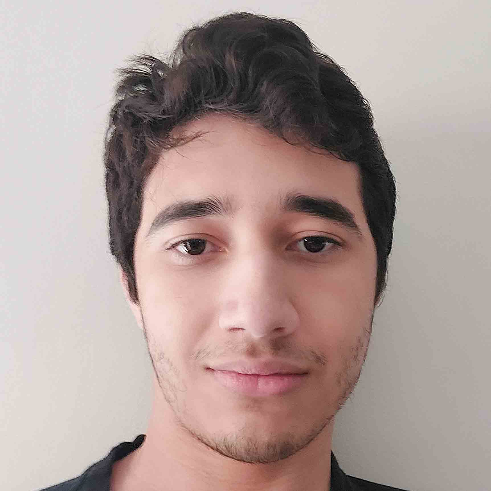 Murilo, aluno de Engenharia Elétrica, posando em um ambiente interno com um fundo claro. Ele tem cabelos escuros e uma expressão neutra.