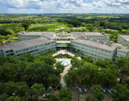 Faculdade de agronegócio campus Presidente Prudente: vista aérea do campus Unoeste cercado por vegetação, jardins e áreas verdes, destacando a arquitetura imponente e a integração com o meio ambiente. O cenário evidencia infraestrutura completa e moderna, ideal para o desenvolvimento de atividades acadêmicas, pesquisa e convivência dos estudantes do curso de agronegócio.