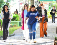Faculdade de agronegócio campus: alunos caminham por uma trilha arborizada dentro do campus, rodeados por jardins e árvores, em ambiente de integração e bem-estar. A imagem mostra a diversidade dos estudantes e o clima acolhedor, ressaltando a importância do convívio social e da conexão com a natureza durante a formação acadêmica em agronegócio.