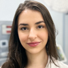 Imagem de Luiza, aluna do curso de medicina no campus Jaú, vestindo jaleco branco. O fundo apresenta elementos técnicos como monitores e equipamentos médicos, reforçando o contexto acadêmico e prático voltado para a formação médica.