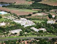 Vista aérea do campus 2 da Unoeste, com diversos blocos acadêmicos cercados por áreas verdes, jardins, campos experimentais e estradas internas. O cenário mostra a integração entre infraestrutura universitária e meio ambiente, ideal para atividades do curso de Engenharia Ambiental.
