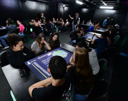 Alunos interagem em grupo na Sala Betha, utilizando mesa digital no curso de Publicidade e Propaganda. 