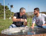 Professor orienta aluno do curso de Agronomia da Unoeste, campus Presidente Prudente, em análise de água e monitoramento ambiental. A atividade ao ar livre utiliza instrumentos científicos, demonstrando o foco em sustentabilidade e tecnologia no agronegócio.