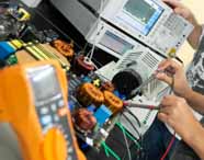 Bancada de laboratório de Engenharia Mecatrônica da Unoeste repleta de componentes eletrônicos, bobinas de cobre, multímetro laranja e analisador de espectro digital. Estudantes utilizam sondas para medições, destacando o ensino prático e tecnológico do curso.
