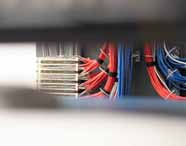 Detalhe de painel técnico com cabos organizados em feixes vermelhos, azuis e brancos, presos por abraçadeiras pretas. Estrutura típica de sistemas elétricos e automação, ilustrando a infraestrutura avançada disponível aos estudantes de Engenharia Mecatrônica na Unoeste.